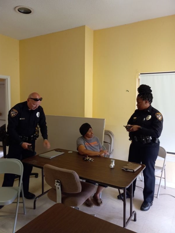 Two police offers chatting with a resident at a community meeting.