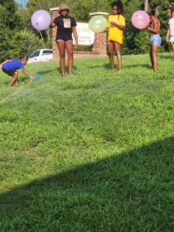 Young girls and boys playing with water balloons.