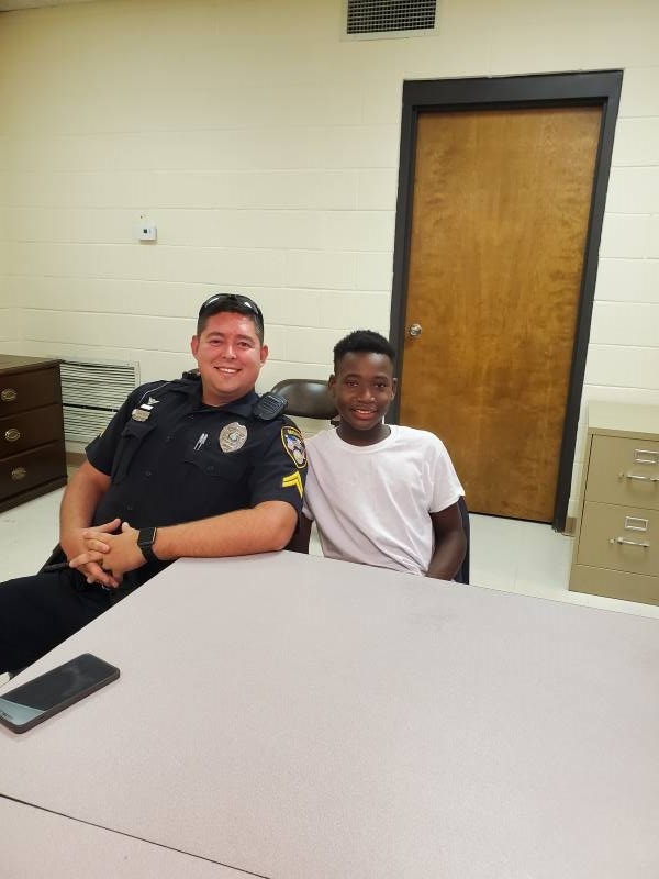 An officer and a young boy sitting next to each other.