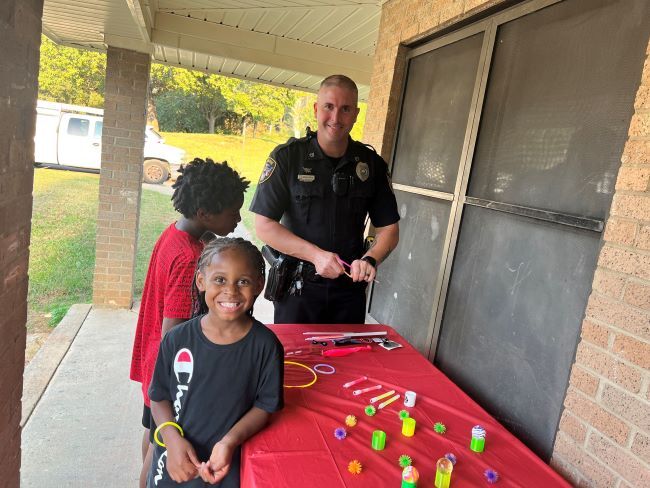 Two children and an officer standing at a display table. 