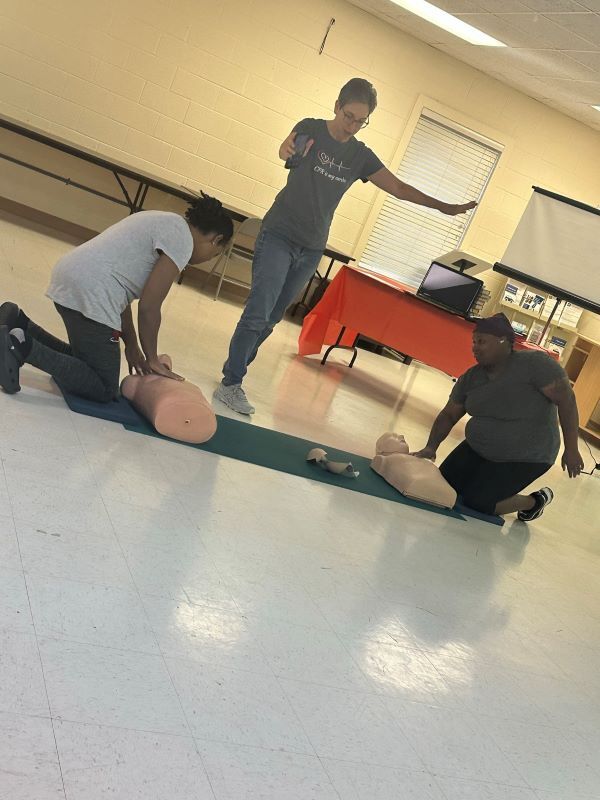 Instructor teaching CPR to students using adult training dummies. 