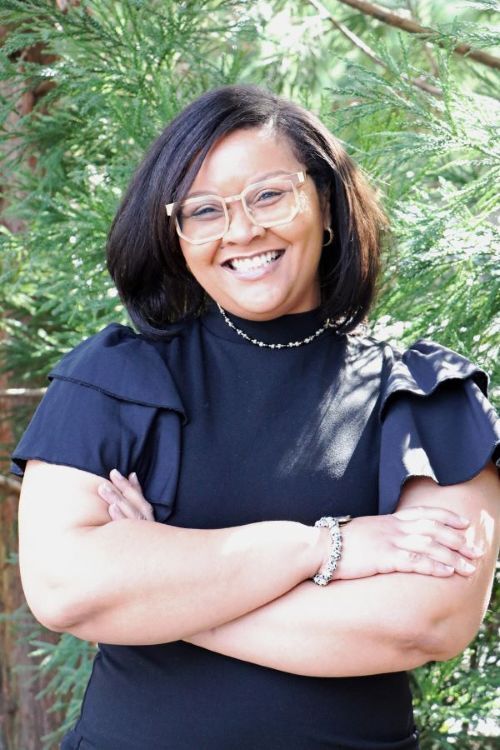 Timica Melvin, Executive Director smiling with arms crossed and standing outside. .jpg