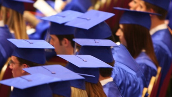 Graduates in a row wearing their cap and gown. 