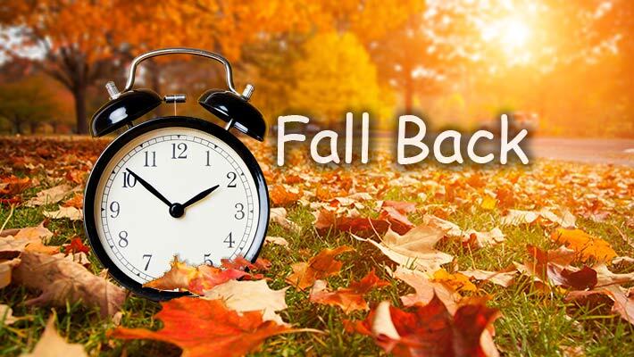 An alarm clock surrounded by leaves and the text, Fall Back.