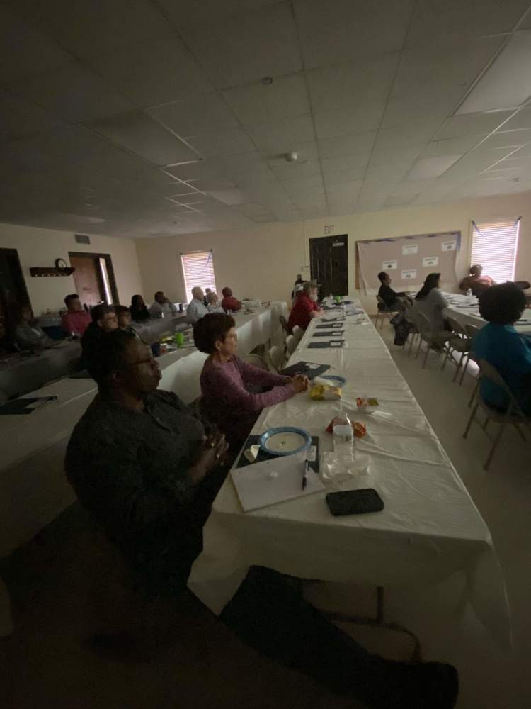 Orientation participants at tables listening to presentation