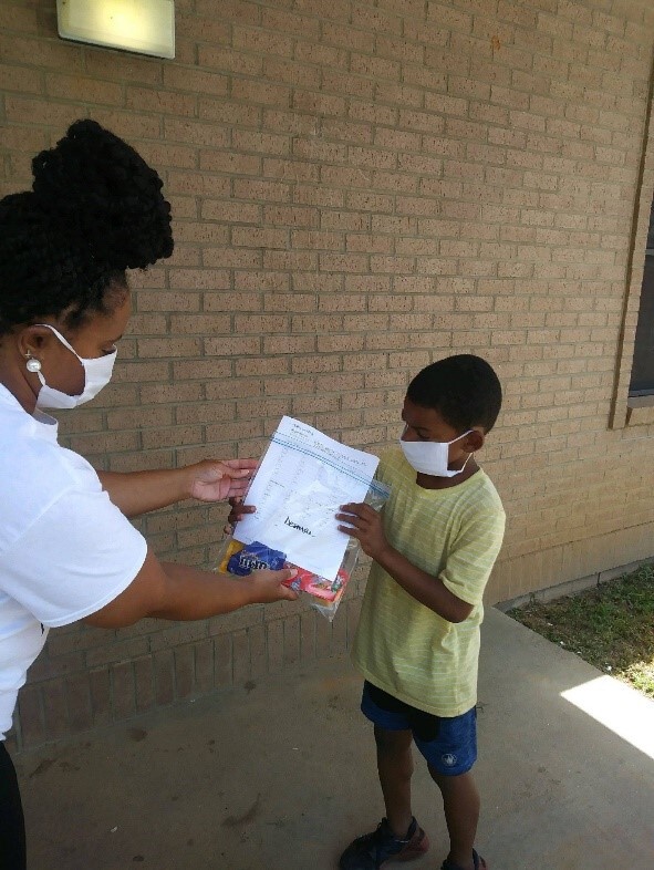 Anna McRae, ED giving packet to student